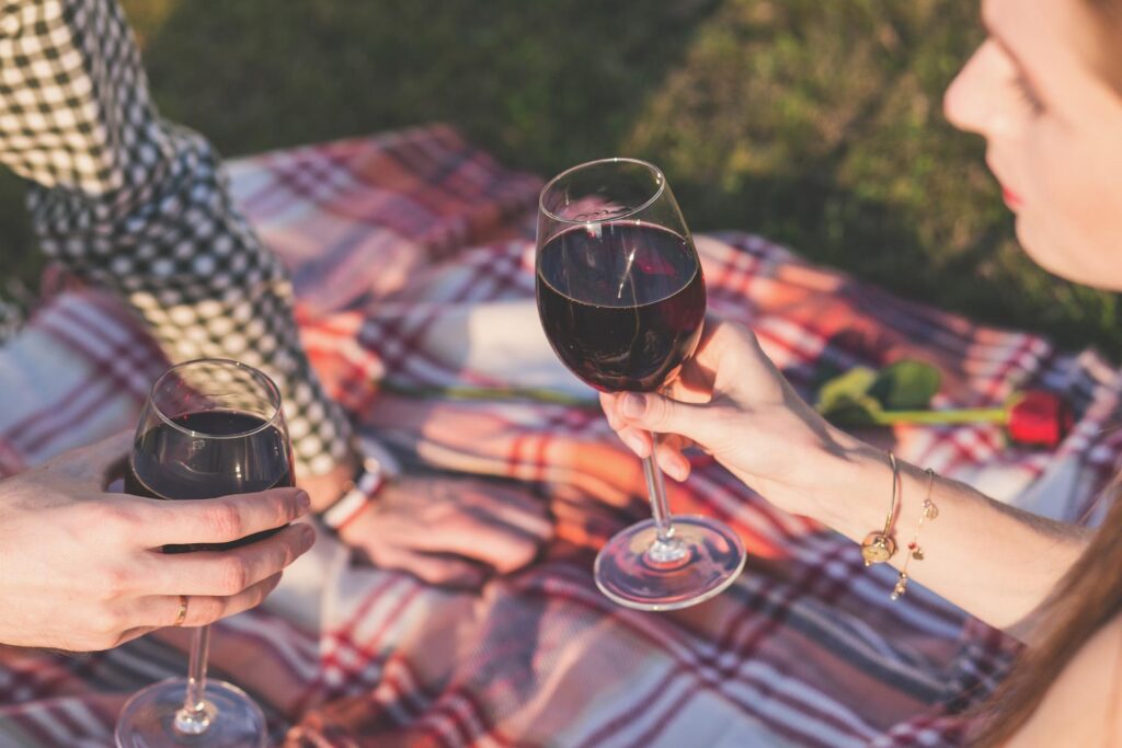 couple faisant un picnic avec un verre de vin rouge